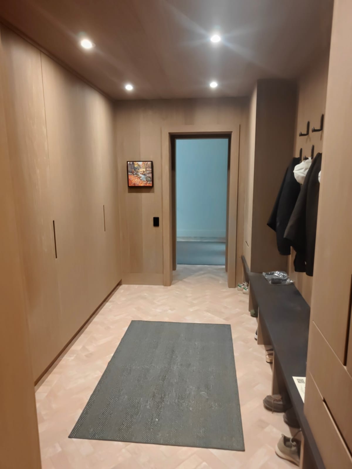 Finished mudroom at 23 Forest Drive, Collingwood, with built-in wood cabinetry, a herringbone floor and a bench with coat hooks