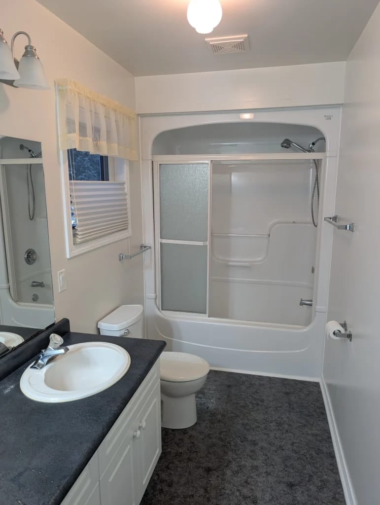 Builder-grade tub and shower combination in the Wasaga Beach bathroom before the Mighton Construction renovation