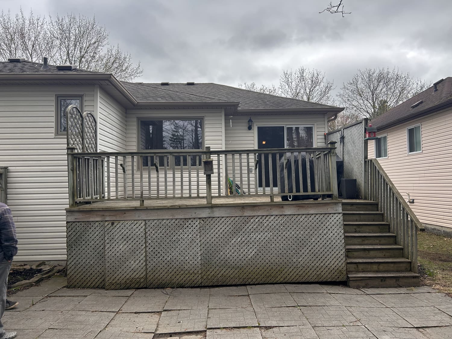 Old weathered deck with lattice skirting and worn paving stones at 46 Timberland Cres in Wasaga Beach before the Mighton Construction rebuild