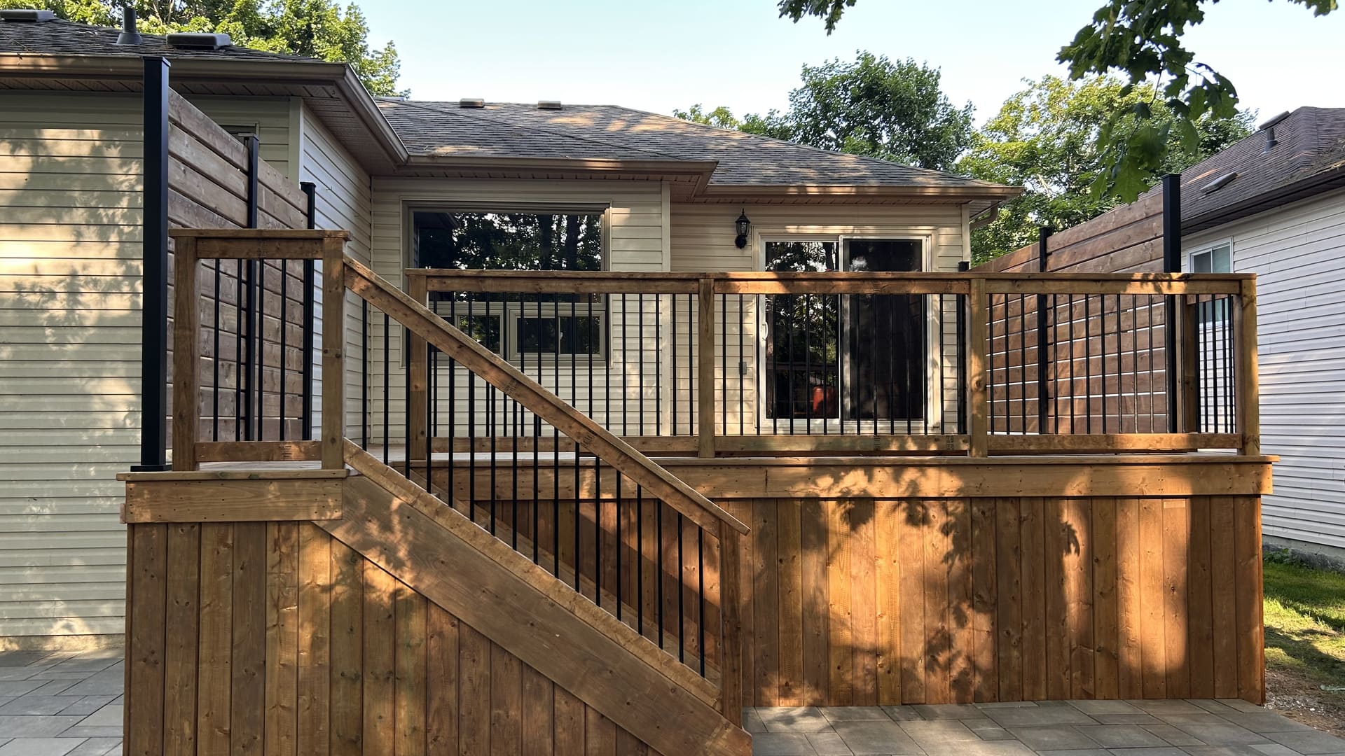 Finished pressure-treated deck with aluminum railings and a paving stone patio at 46 Timberland Cres in Wasaga Beach