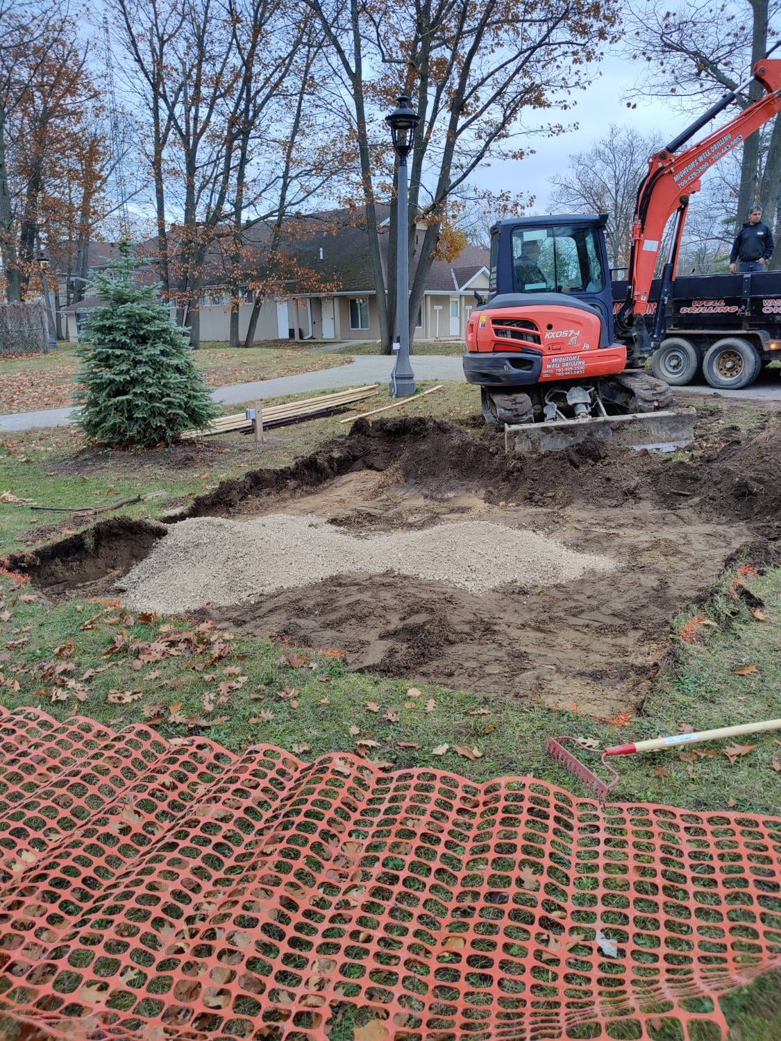 Excavation and stone base for the new concrete pad beside Town Hall in Wasaga Beach, with an excavator at work
